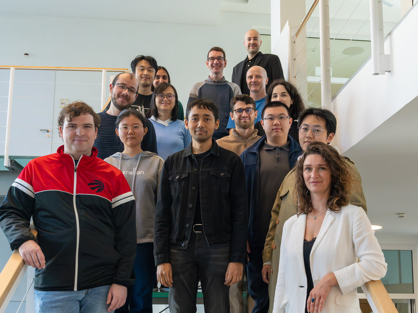 Department of Nanophotonics, Integration, and Neural Technology (NINT) Several individuals positioned on a staircase inside a modern building, displaying a mix of casual and semi-formal outfits, indicating a professional setting.